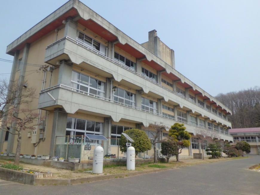 3階建ての校舎の前にいろいろな種類の木が植えられている下川崎小学校の外観写真