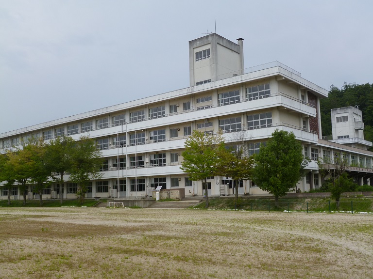 校庭の奥に4階建ての校舎が建っている蓬莱小学校の外観写真
