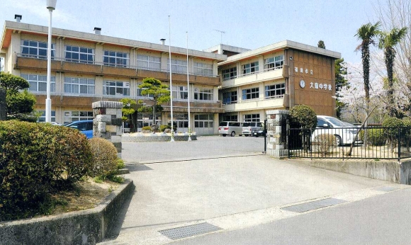 校門の先に駐車スペース、3階建ての校舎がある大鳥中学校の外観写真