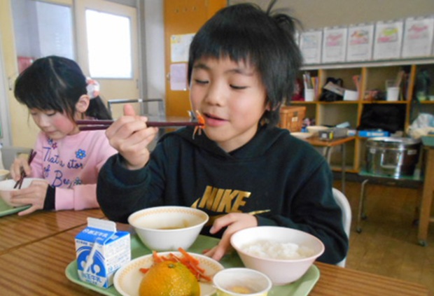 給食のいか人参を食べている佐倉小学校の児童の写真