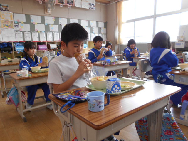 教室の自席で給食を食べている生徒たちの写真