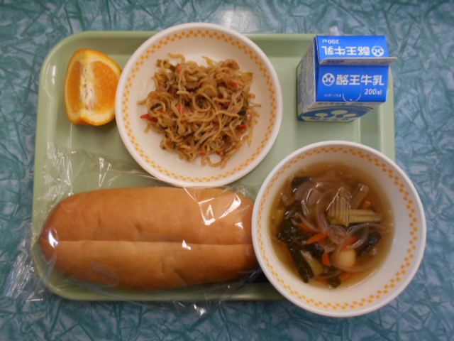 若草色のトレーの上に、コッペパン、うずらの卵スープ、おかず焼きそば、パックの牛乳、いよかんが乗っている写真