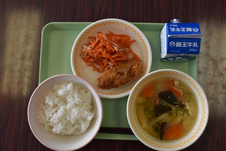 若草色のトレーの上に、ごはん、みそ汁、いかにんじんとゆずみそチキンカツが盛り付けられた皿、パックの牛乳がのっている写真