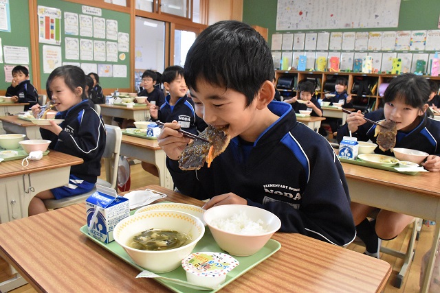大きなステーキに笑顔でかじりついている児童たちの写真
