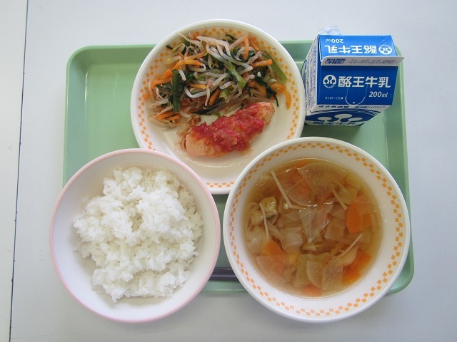 薄緑色のトレーに、ごはん、とりささみのトマトソース煮とにらのおひたしが盛られた皿、真鯛と野菜のスープ、パック牛乳が乗っている写真