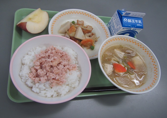 薄緑色のトレーに、ももごはんふりかけが乗ったごはん、さといものうま煮、豚汁、パック牛乳、りんごが乗っている写真