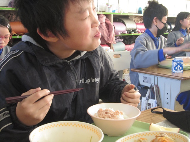 おいしそうに給食を食べている男子生徒の写真