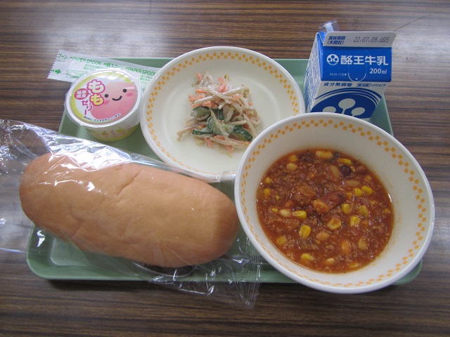 若草色のトレーの上に、米粉パン、チリコンカン、ごぼうサラダ、パックの牛乳、ももゼリーが乗っている写真