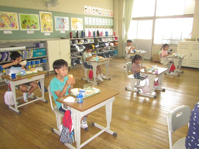 教室の自席で給食を食べている児童たちの写真