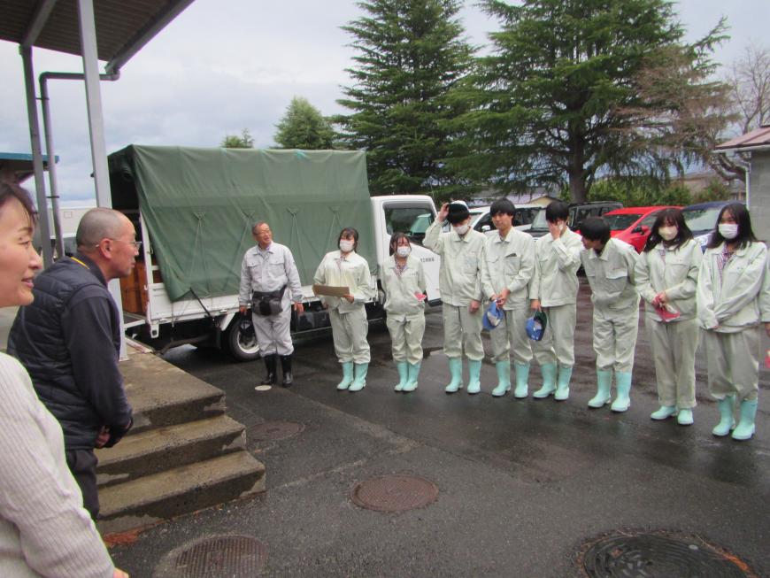 長靴を履き、作業着を着た福島明成高等学校の生徒8名が横一列に並んでいる写真