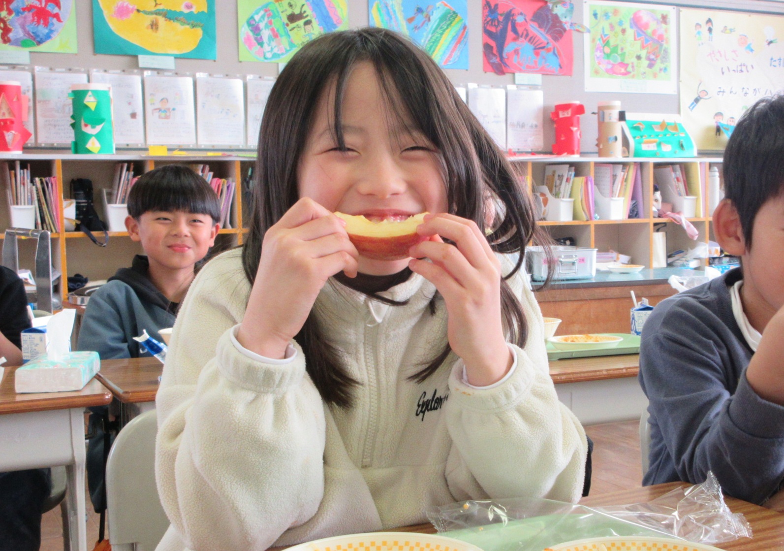 給食で出たりんごを食べる女の子の写真