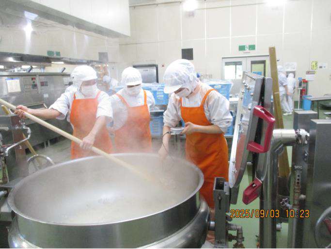 実習生が釜の食材をかき混ぜている写真