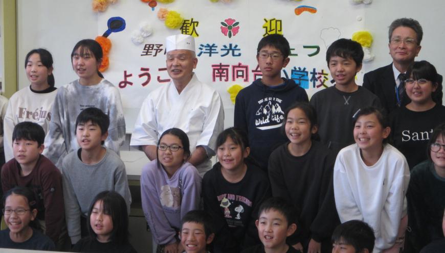 野崎氏を中心に生徒達が集まり、記念撮影をしている写真