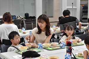 参加者の母子が3人並んで給食を食べている写真