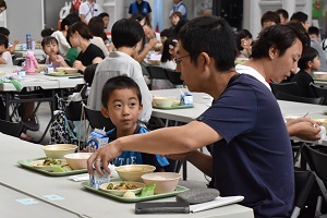 参加者の父子が会話をしながら給食を食べている写真