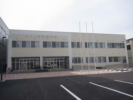 うすいベージュの外壁に「ふくしま支援学校」の文字が設置された2階建ての管理棟の外観写真