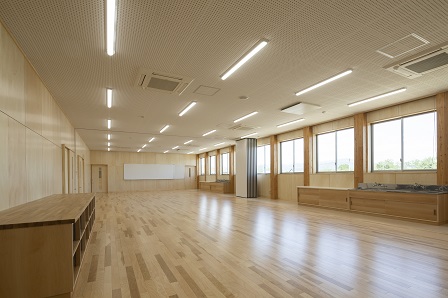 床と壁が木目調で、壁側に背の低い棚がいくつも設置されているものづくり棟の室内の写真
