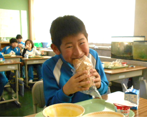 透明の袋から出したきなこ揚げパンをうれしそうに食べている男子生徒の写真
