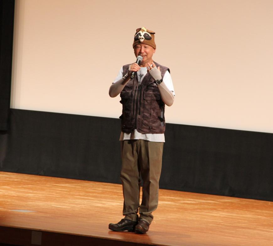 舞台の中央にたって講演をしている佐々木洋さんのアップの写真