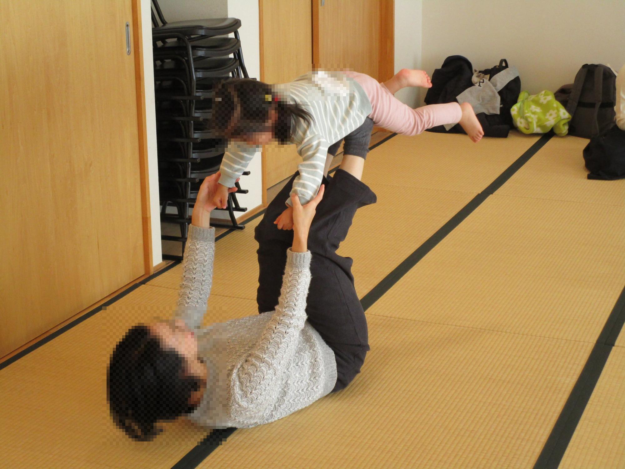 お母さんがお子さんと飛行機体操している様子