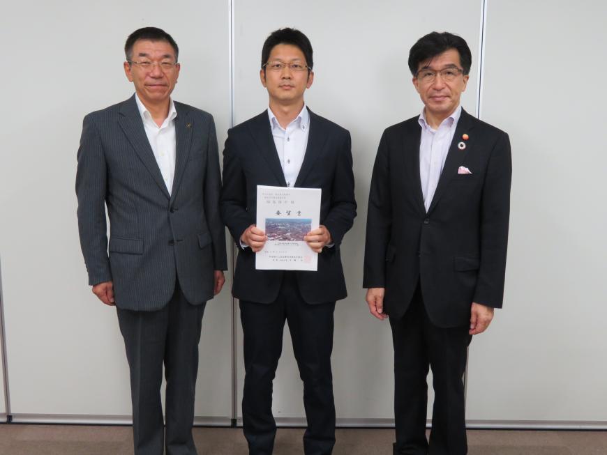 市長とスーツを着た男性2名が並び、真ん中の男性が要望書を持って記念撮影している写真
