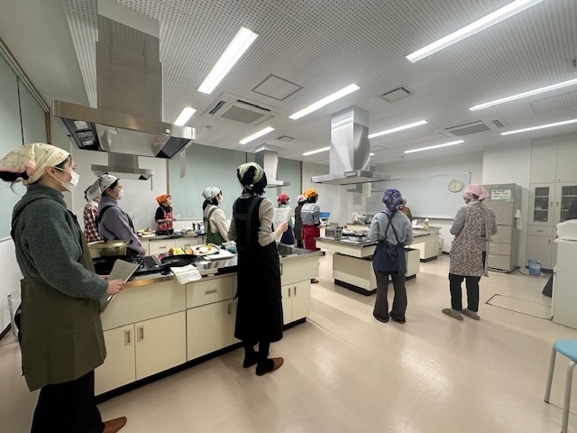 調理室で参加者の人たちが説明を聞いている写真