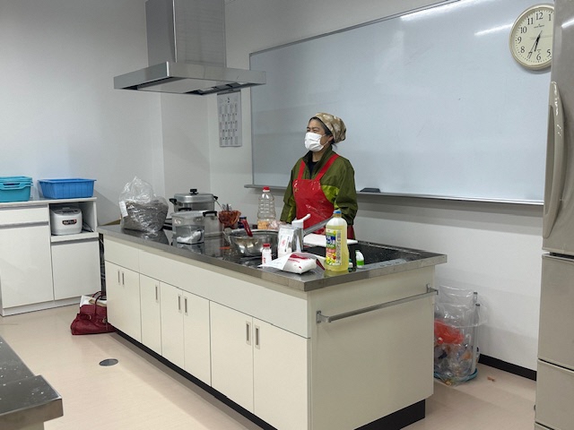 講師の女性が調理台の前で話をしている写真