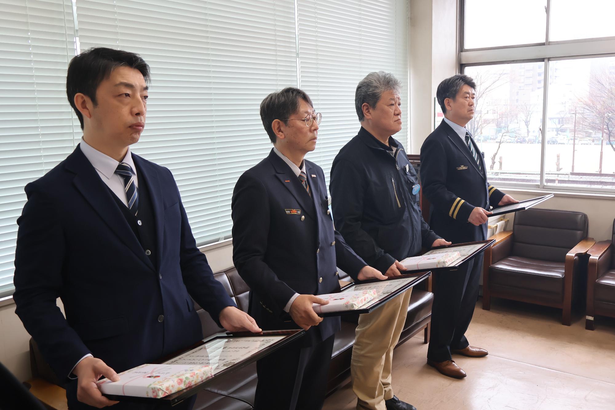 受章者4名が感謝状と記念品を持って横一列に並んでいる写真