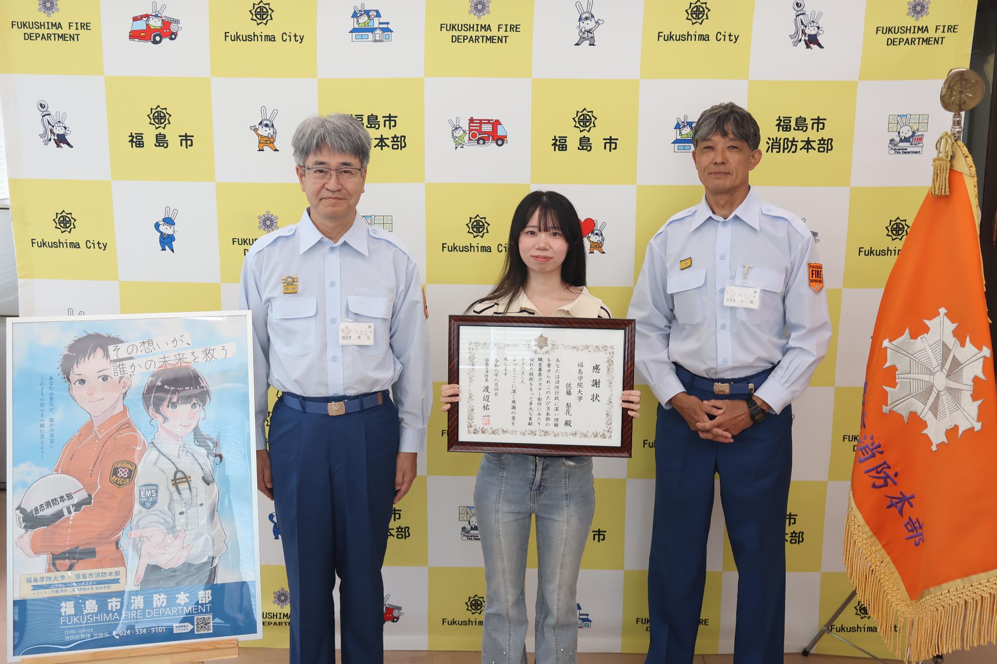 福島市消防長、受賞者の福島学院大学学生、消防本部次長が並んでの記念撮影