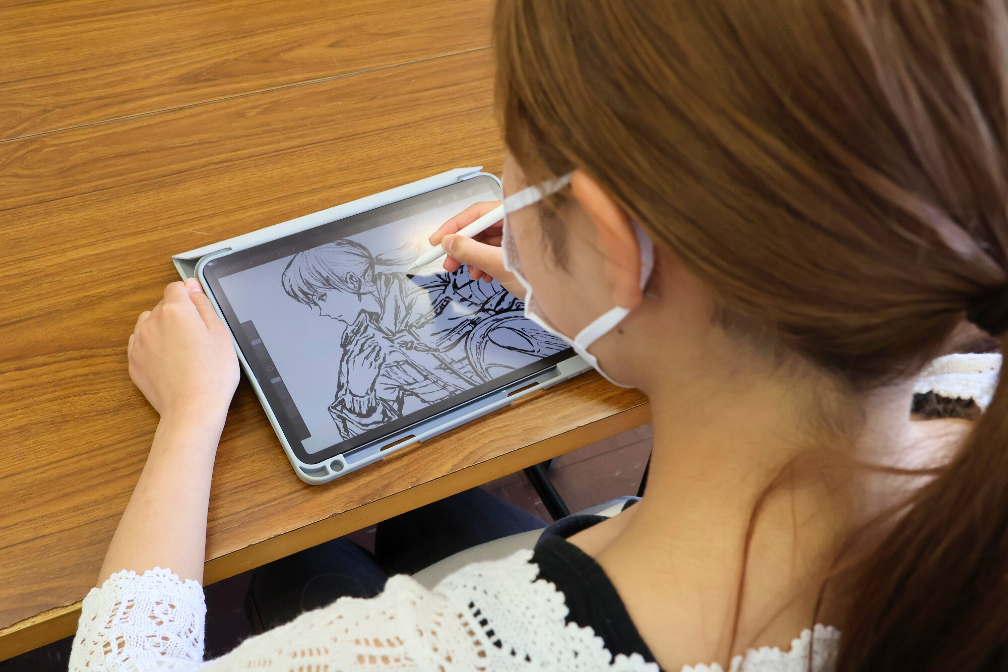 福島大学美術研究会の学生がタブレット端末でポスターのイラストを描いている写真