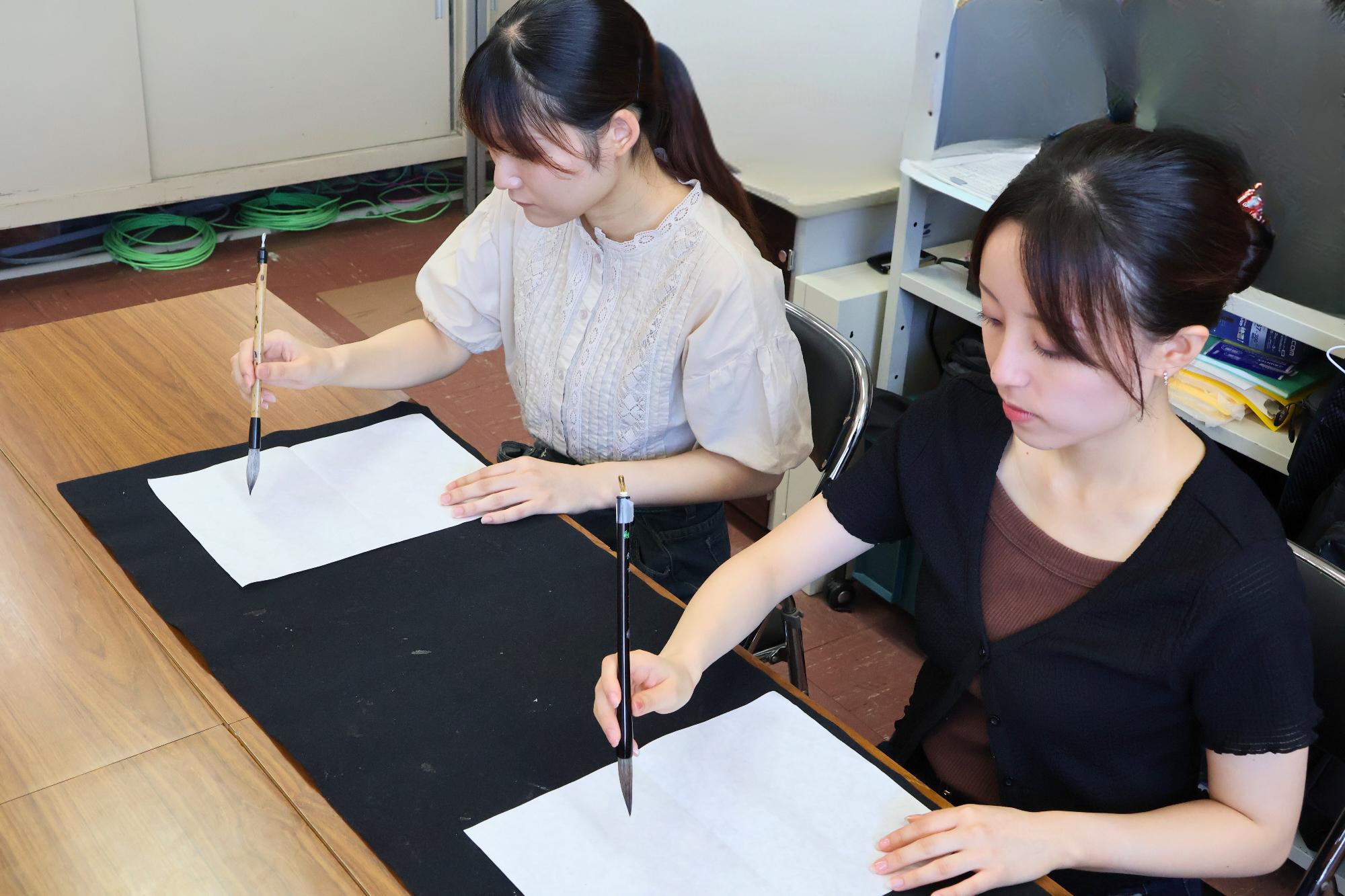福島大学書道研究会の2名が各々に揮毫する様子の写真