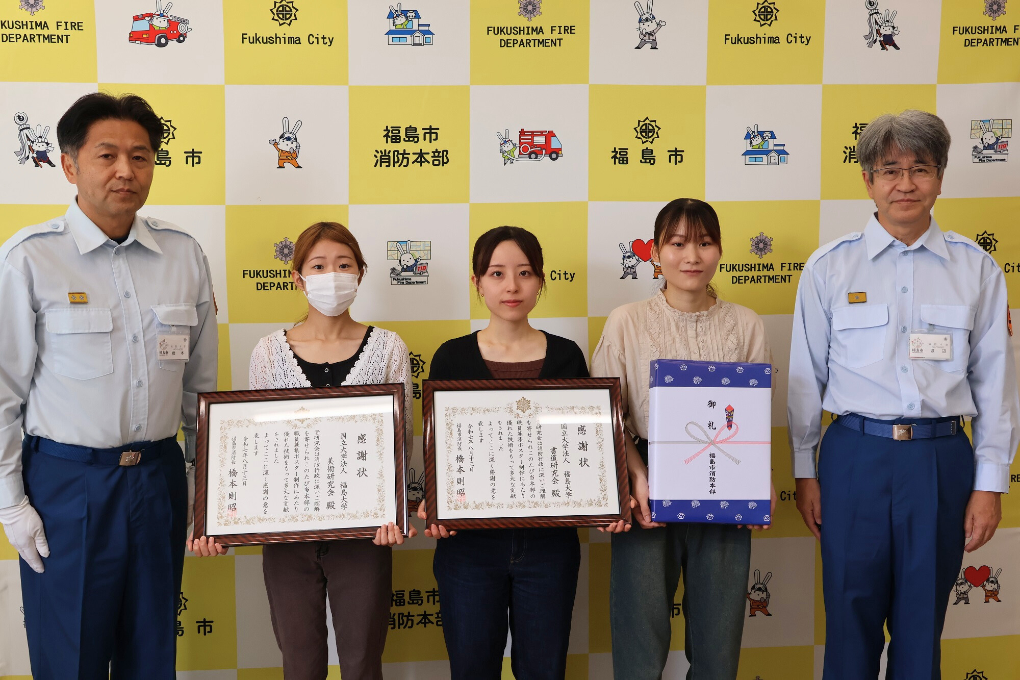 福島大学の学生3名が感謝状を持ち消防長、消防本部次長と共に横一列に並んだ記念写真