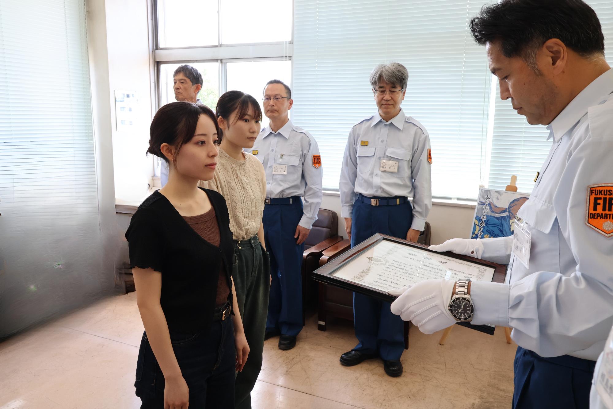 福島大学書道研究会の代表学生が消防長から感謝状を贈呈されている写真