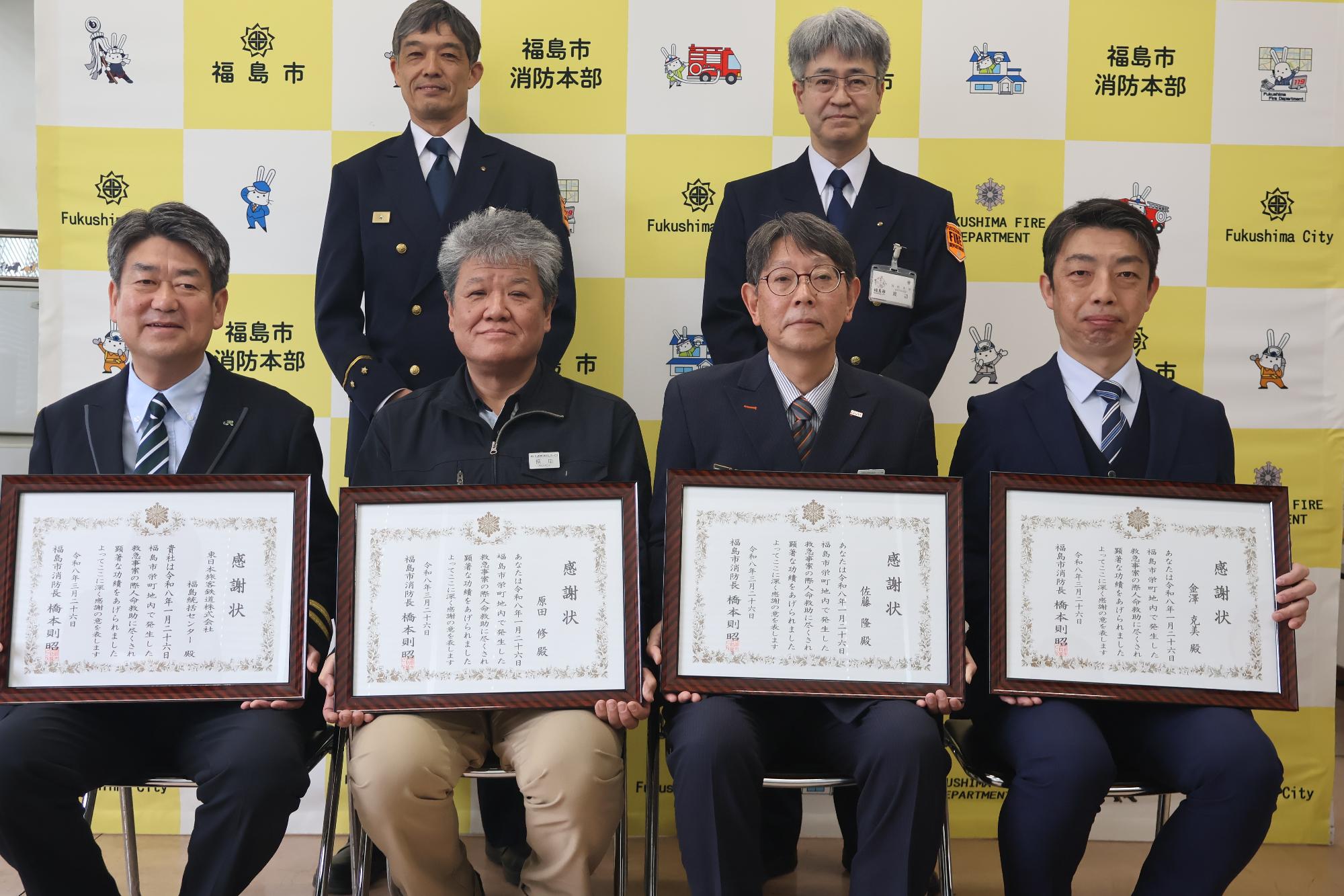 受章者4名が前列で椅子に座り、後列中央に消防本部次長、福島消防署長が立ち並んだ写真