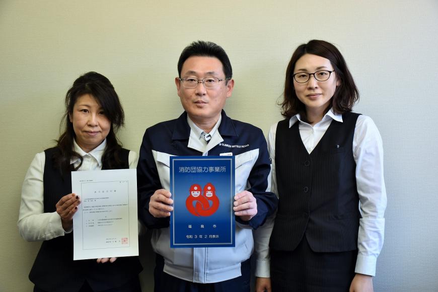 男性と女性が消防団協力事業所表示証を持って3人で撮影している写真