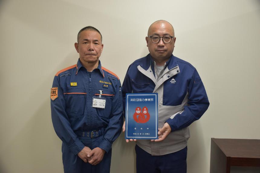 ライト工業株式会社福島営業所の事務所内で男性2人が消防団協力事業所表示証を持っている写真