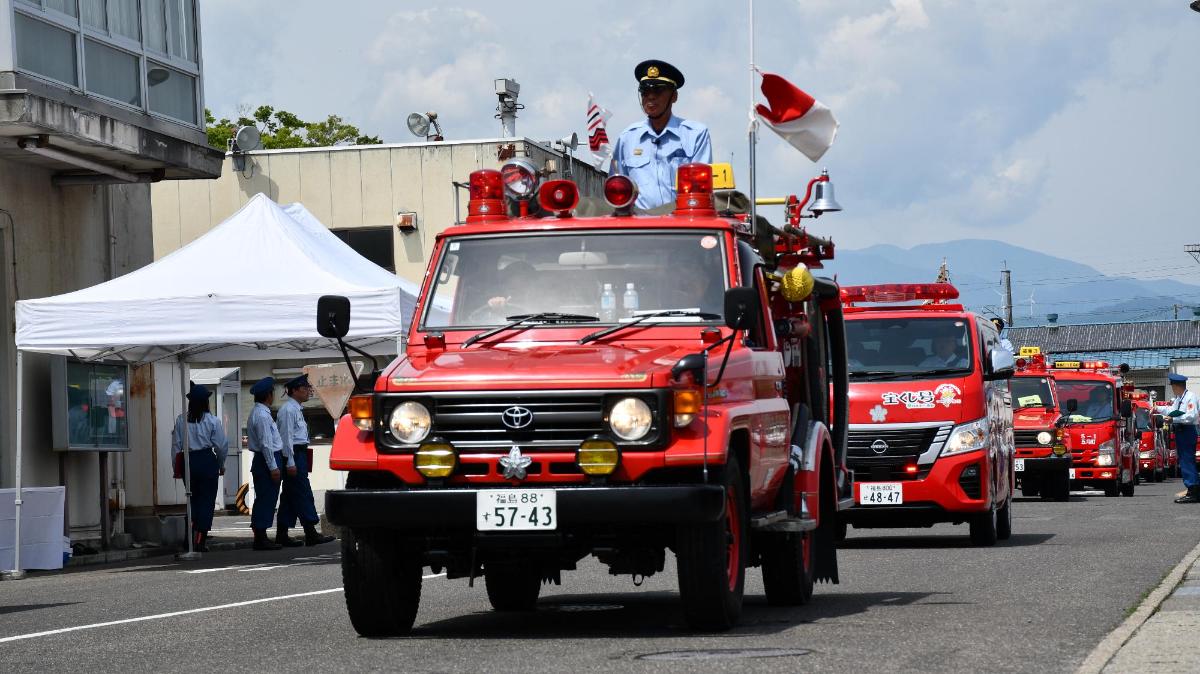 消防団車両部隊が行進している写真