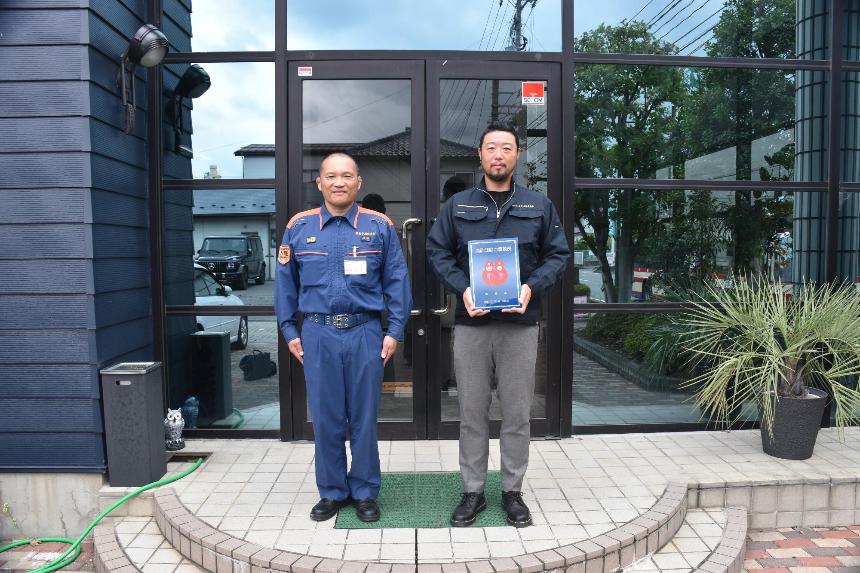 ワイアールテック株式会社の建物の前で男性2人が消防団協力事業所表示証を持っている写真